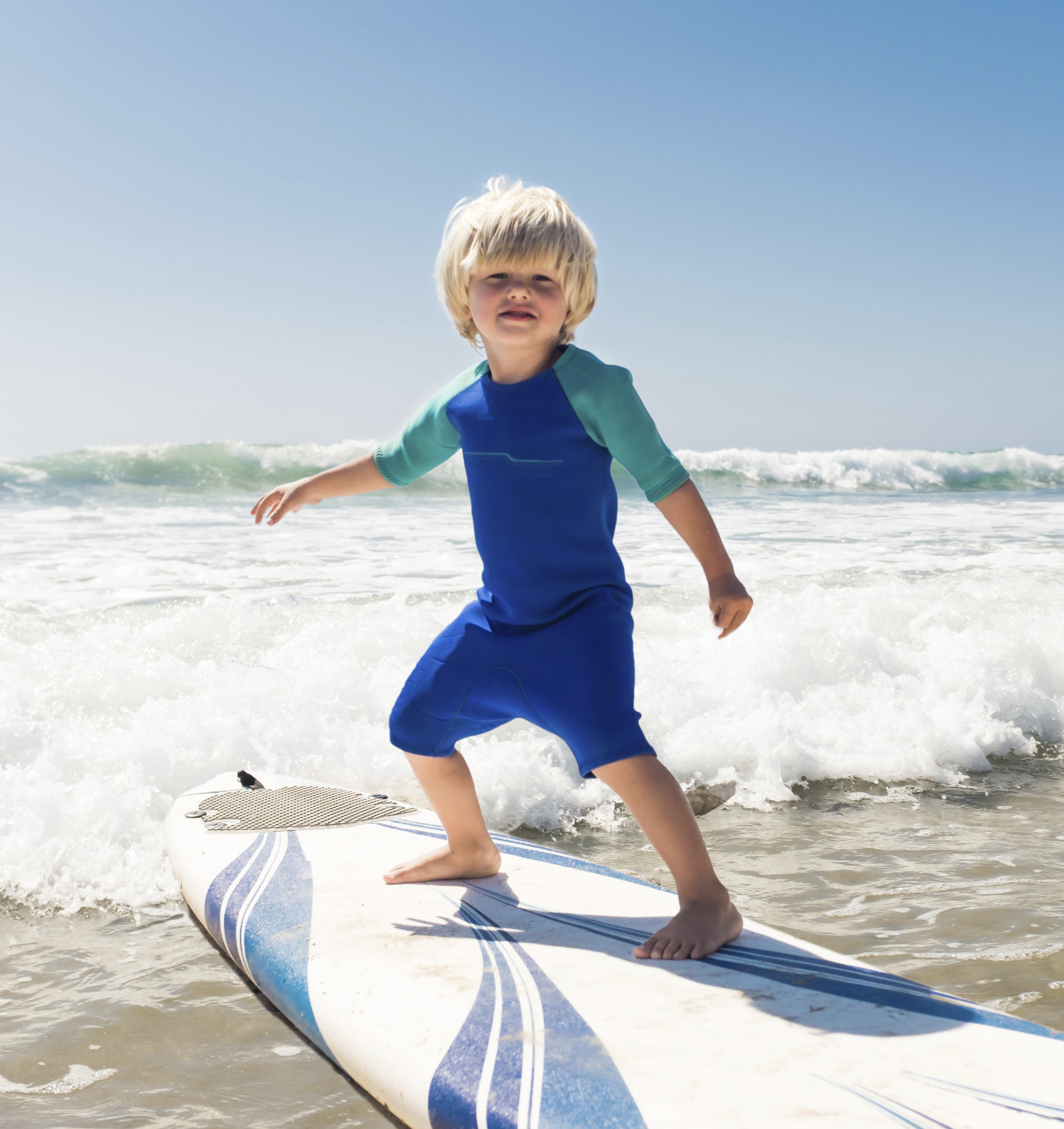 A little boy surfing in the waves.